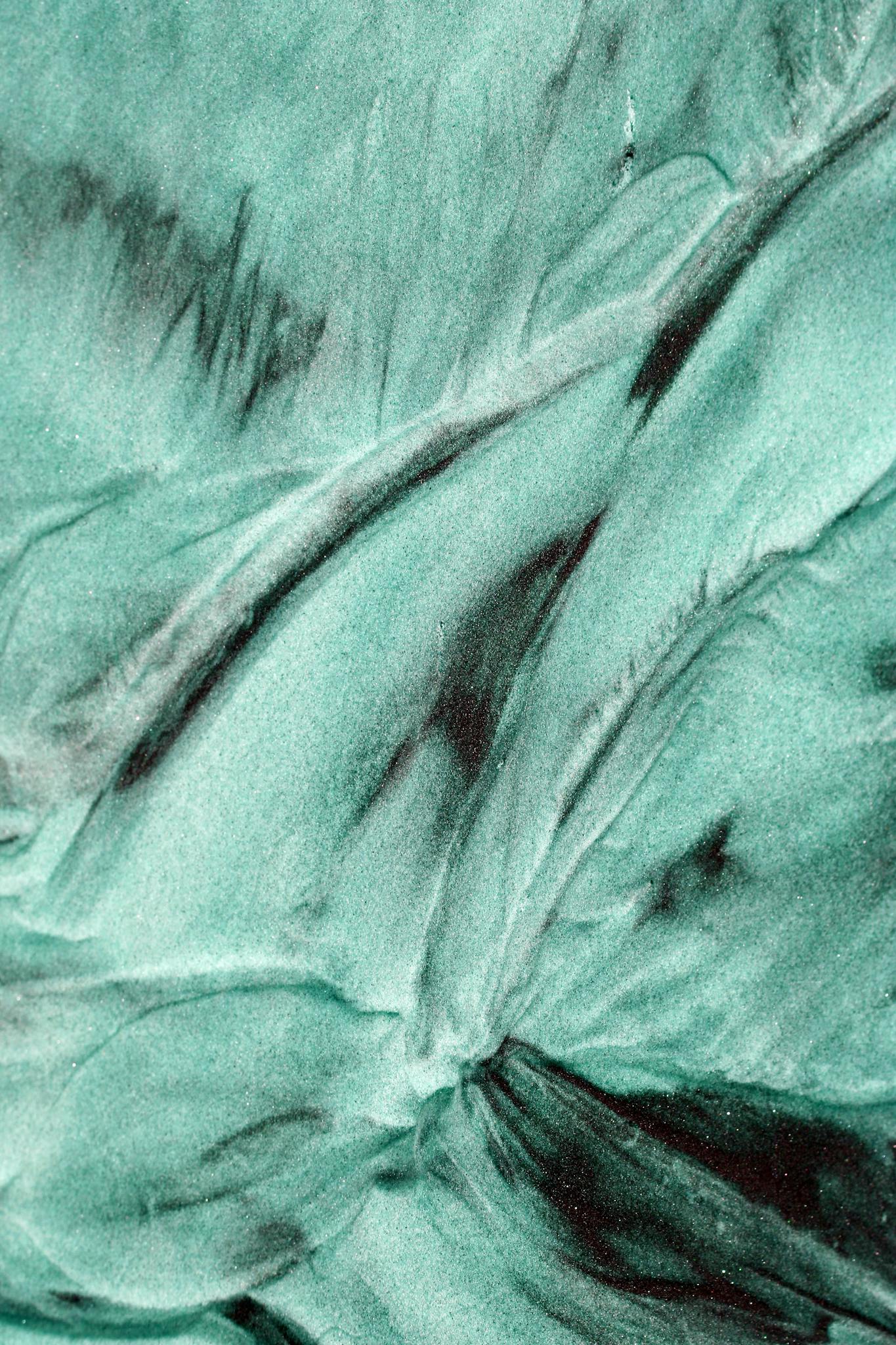 Close-up of a green and black marbled texture with artistic swirls.